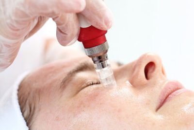 Beautician performs a needle mesotherapy treatment on a woman's face