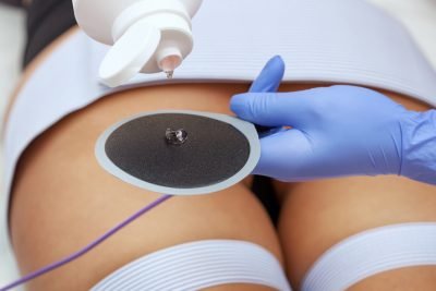 The procedure of myostimulation on the legs and buttocks of a woman in a beauty salon. Caring for the body, reducing excess weight.